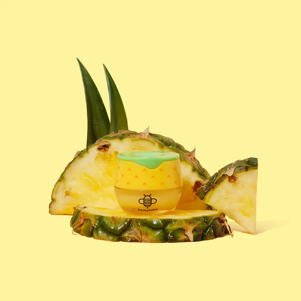 Small container with a bee logo on a pineapple slice against a yellow background