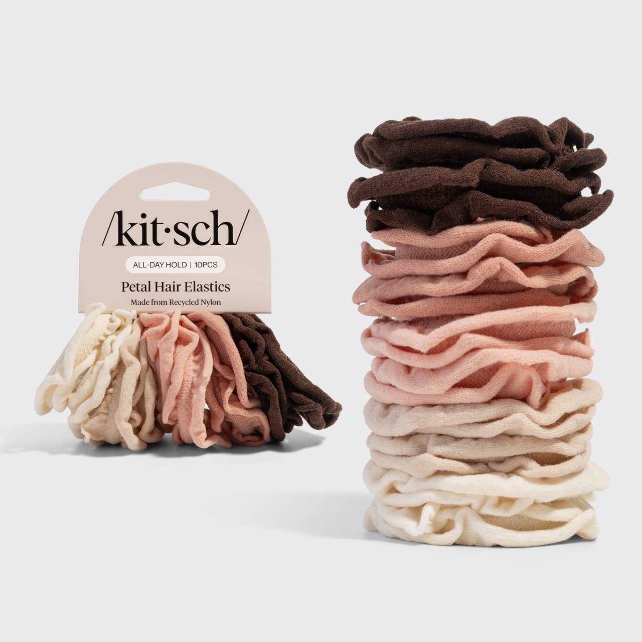Stack of Kitsch hair elastics in various colors with packaging on a light gray background