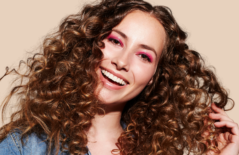 woman with long blonde brown curly hair worn out smiling