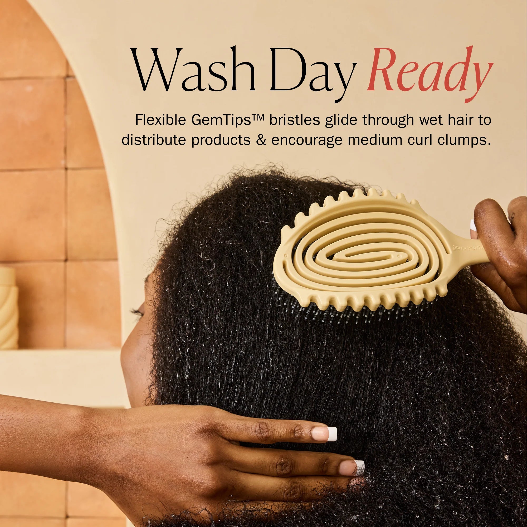 A person with dark curly hair is shown from the back while being brushed with a beige flexible hairbrush. Text at the top reads 'Wash Day Ready' with a descriptive product blurb about flexible GemTips bristles distributing products and encouraging medium curl clumps.