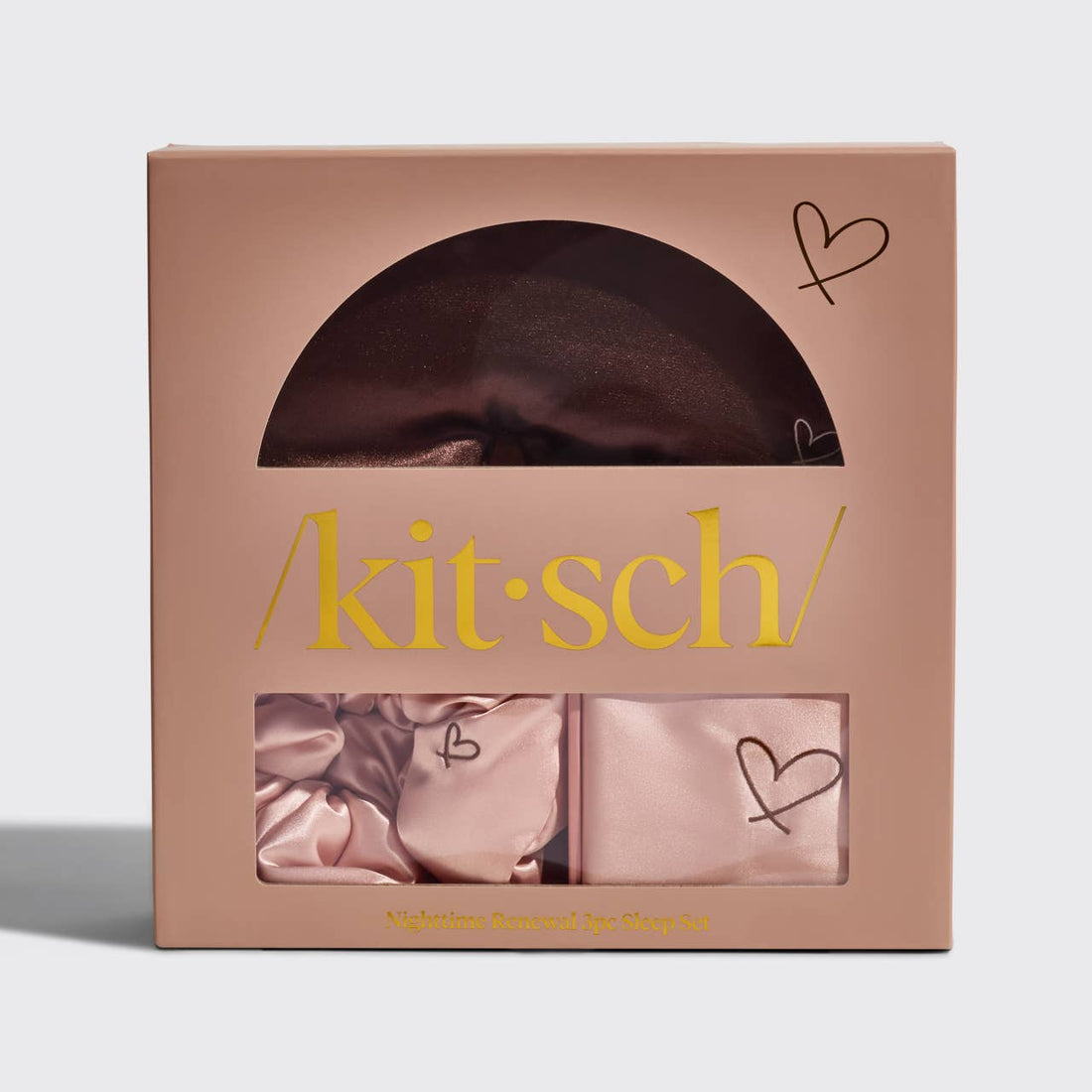 A Kitsch Nighttime Renewal 3pc Sleep Set in a pink box, displaying a satin pillowcase, scrunchie, and eye mask with heart details.
