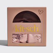 A Kitsch Nighttime Renewal 3pc Sleep Set in a pink box, displaying a satin pillowcase, scrunchie, and eye mask with heart details.