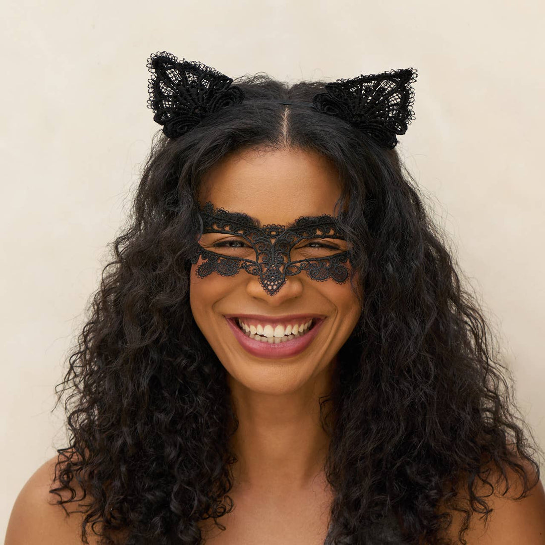 Woman wearing black lace cat ears and mask on a beige background