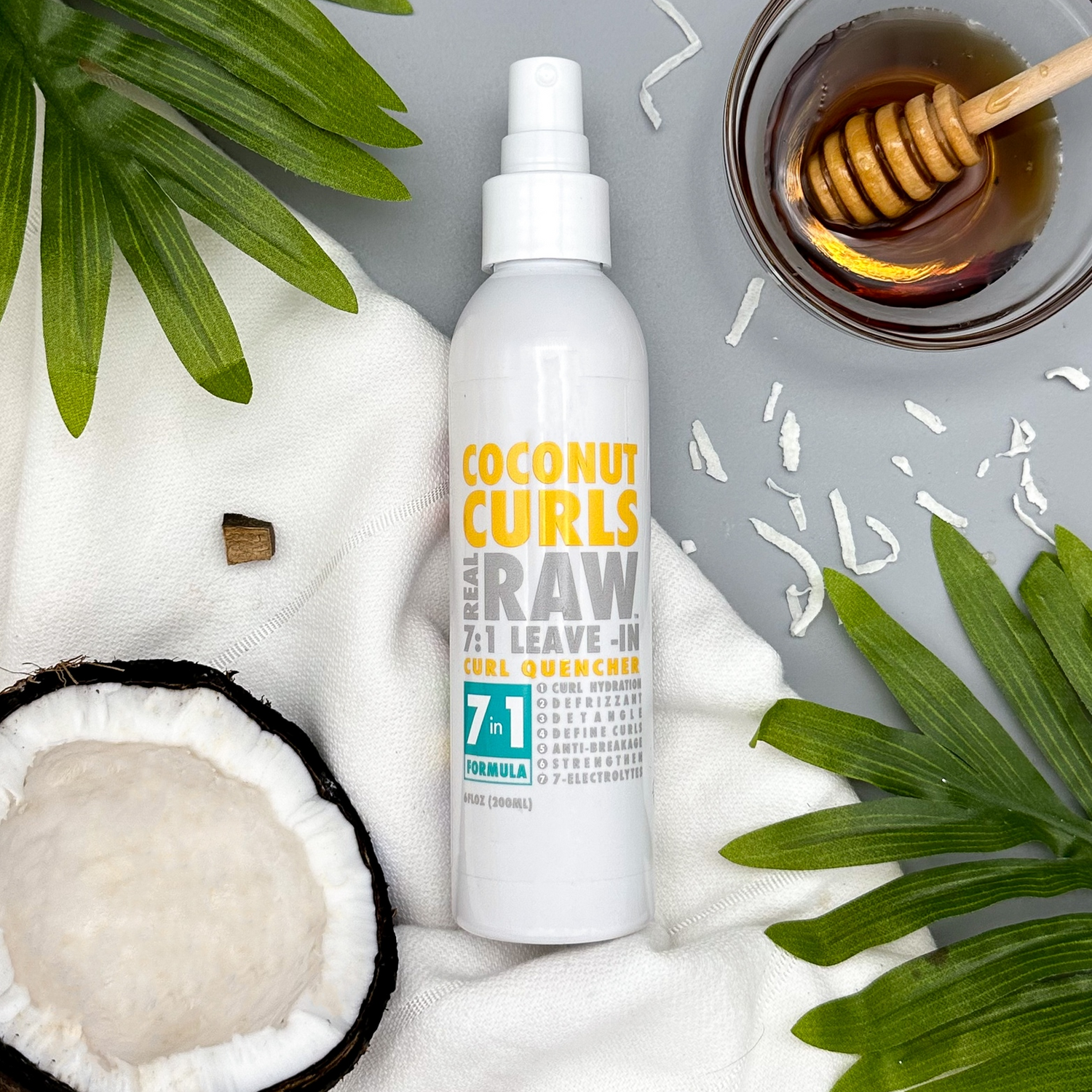Coconut Curls raw hair product with coconut, honey, and leaves on a gray background