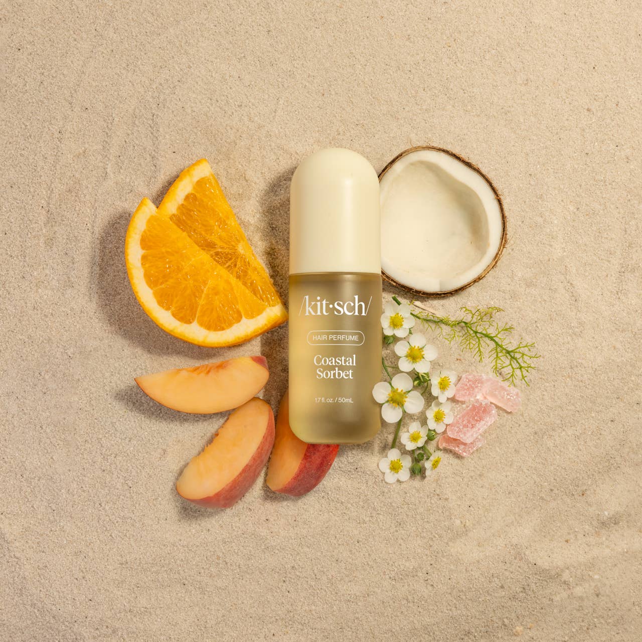 Kitsch Coastal Sorbet perfume bottle surrounded by fruit slices and flowers on a beige background