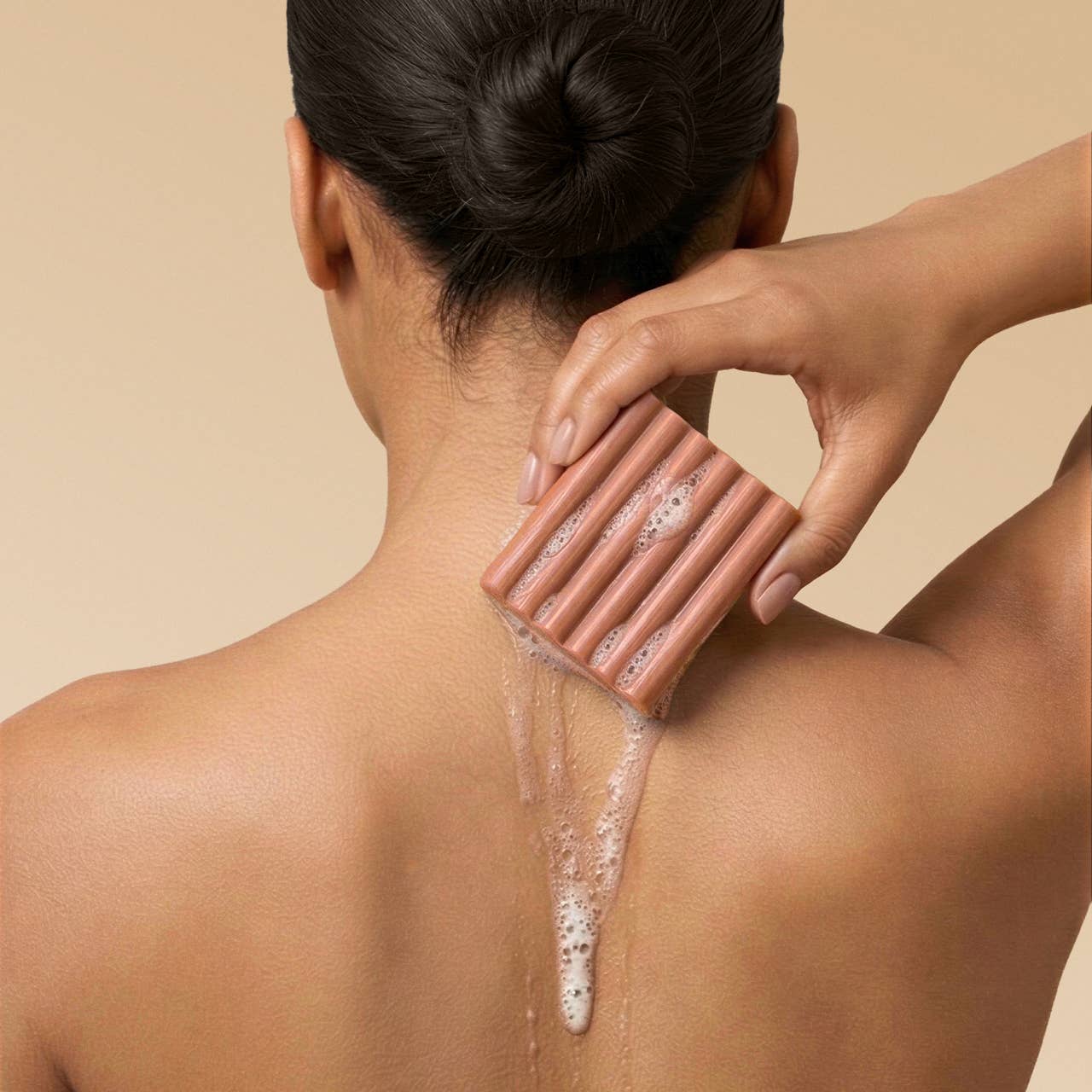 Person using a soap bar on their back against a beige background. Kitsch Amber Shores Body Wash Bar 