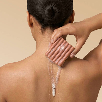 Person using a soap bar on their back against a beige background. Kitsch Amber Shores Body Wash Bar 