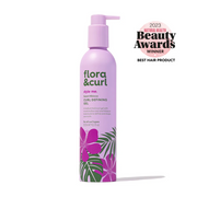 A bottle of Flora & Curl Sweet Hibiscus Curl Defining Gel with a purple label featuring green leaf patterns. The product has won a 2023 Beauty Awards badge.