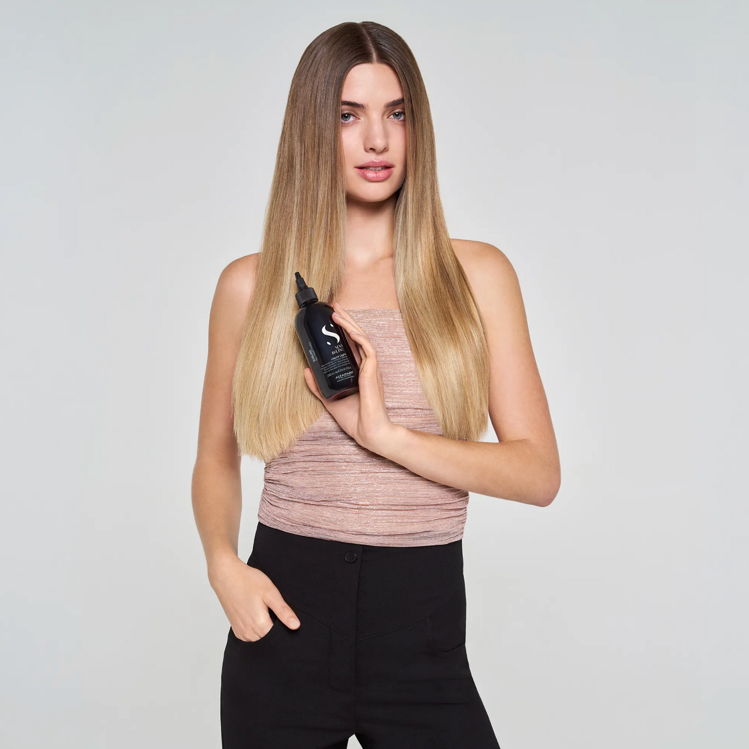 Model holding Alfaparf Milano Semi di Lino Sublime Liquid Light Illuminating Lamellar Water showcasing glossy, smooth and healthy-looking hair after treatment.