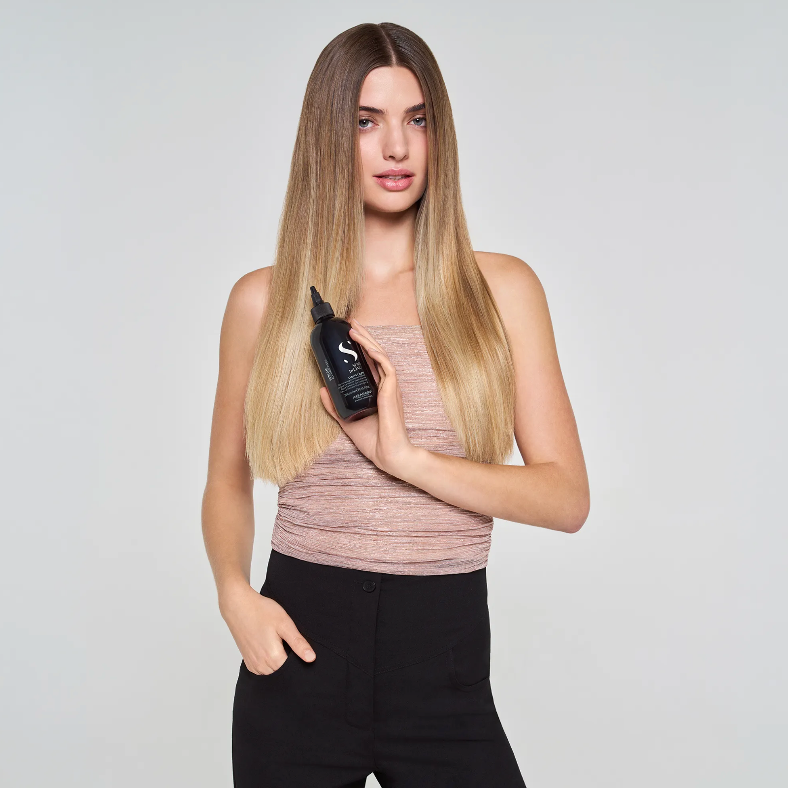 Model holding Alfaparf Milano Semi di Lino Sublime Liquid Light Illuminating Lamellar Water showcasing glossy, smooth and healthy-looking hair after treatment.