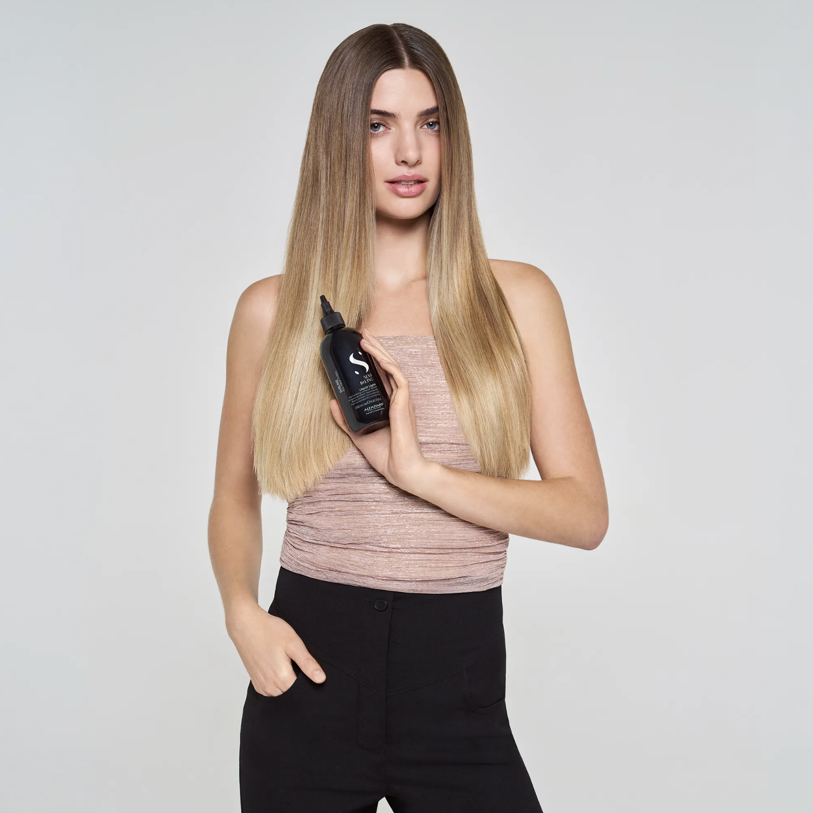 Model holding Alfaparf Milano Semi di Lino Sublime Liquid Light Illuminating Lamellar Water showcasing glossy, smooth and healthy-looking hair after treatment.