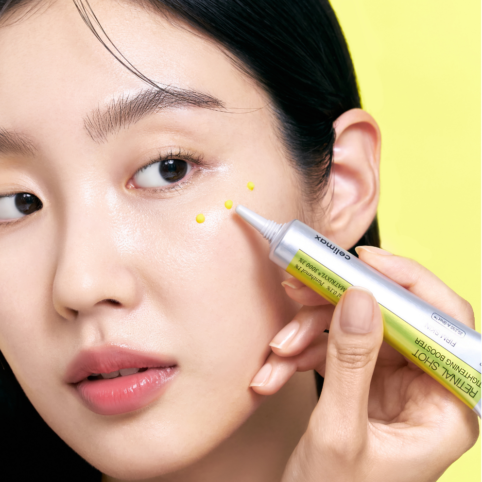 Person applying Celimax Retinal Shot Tightening Booster to their face with a yellow background