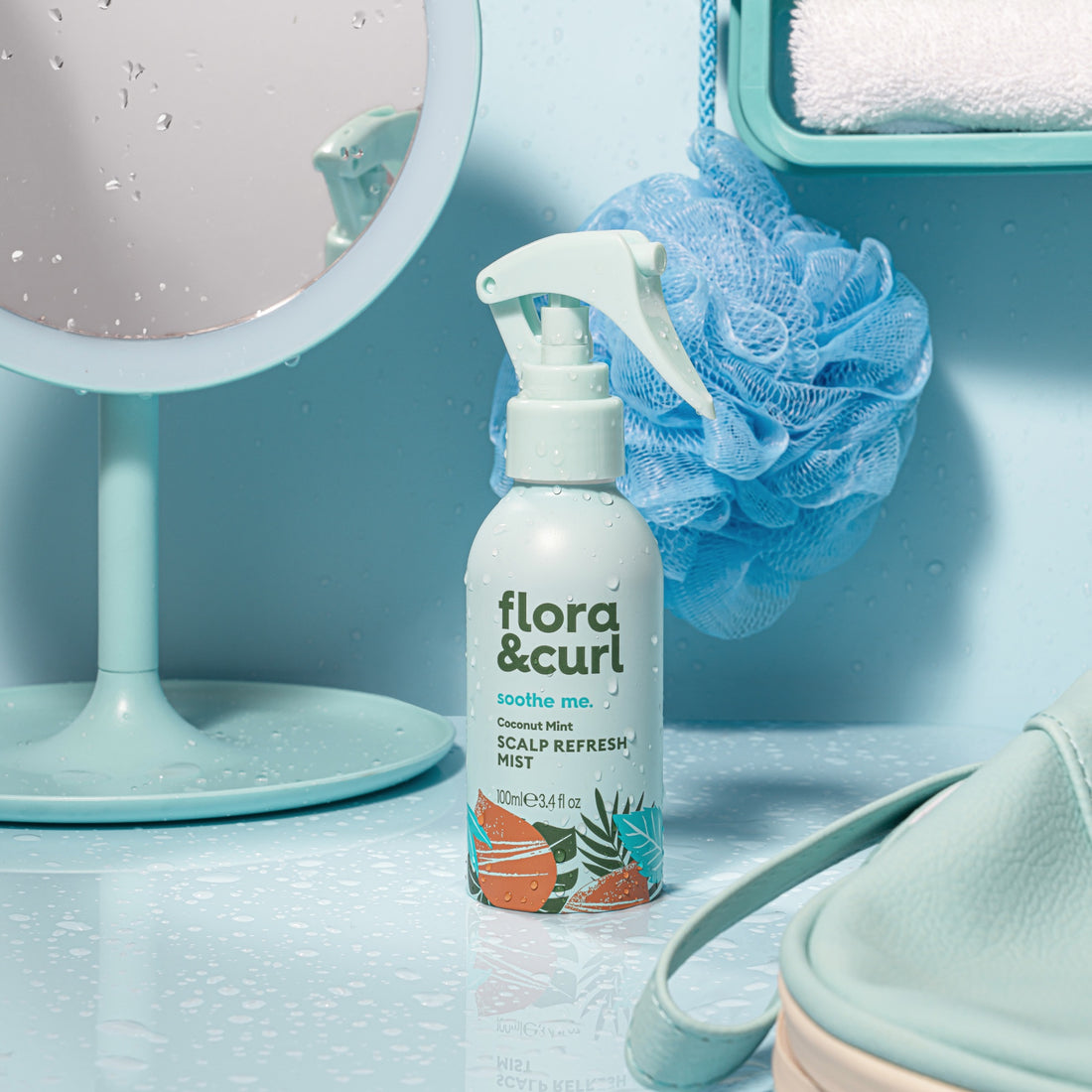 Flora &amp; Curl scalp refresh mist bottle on a bathroom counter with a mirror and loofah in the background.