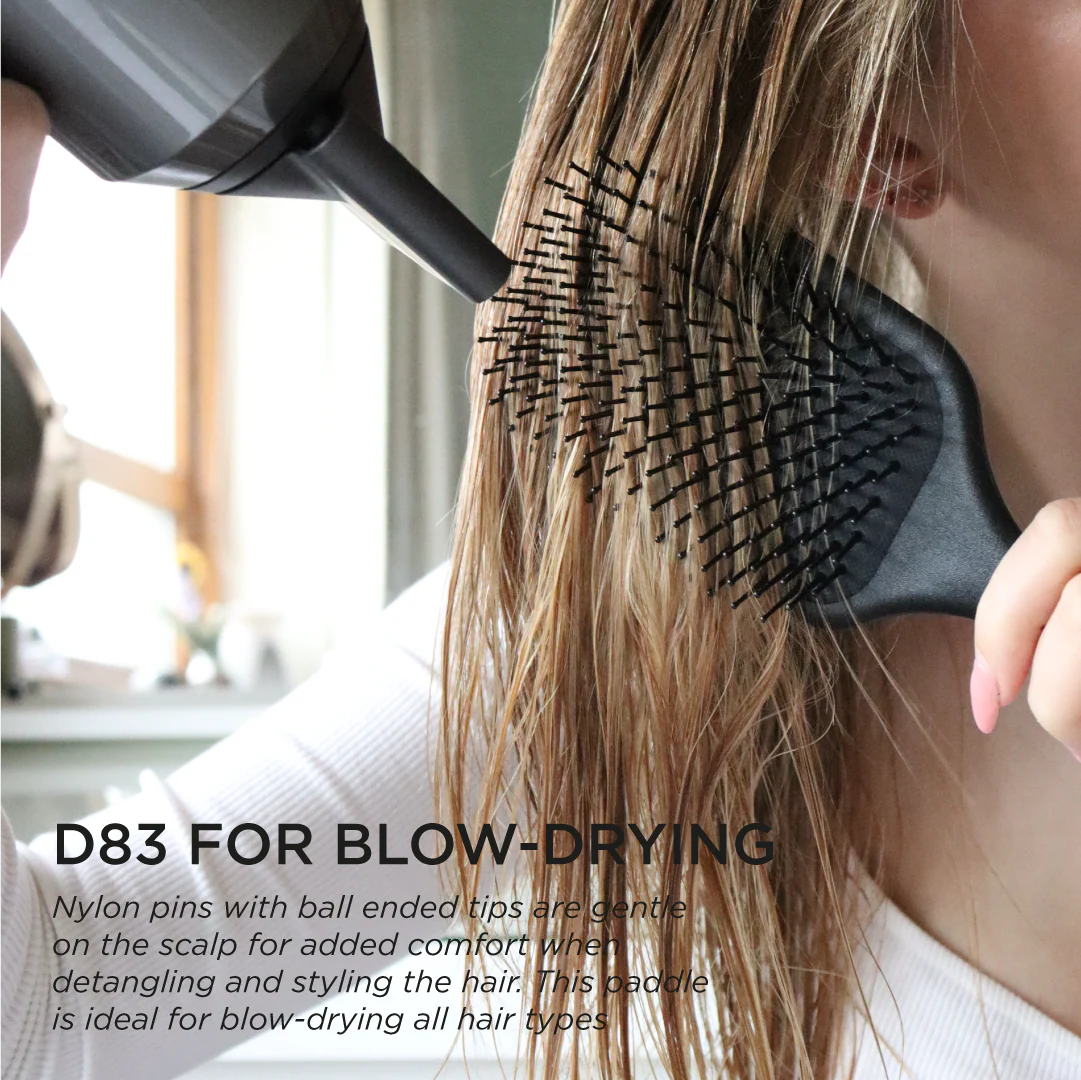 Denman D83 The Gentle Paddle Brush in use during blow-drying, featuring ball-ended nylon pins for gentle detangling, smoothing and comfortable styling.