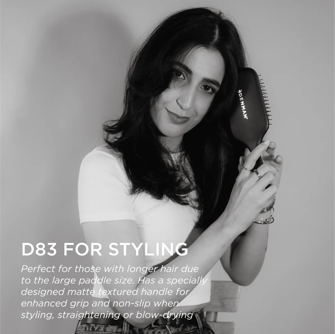 Model holding the Denman D83 The Gentle Paddle Brush, showcasing its ergonomic matte handle and large paddle for styling, straightening and everyday hair care.
