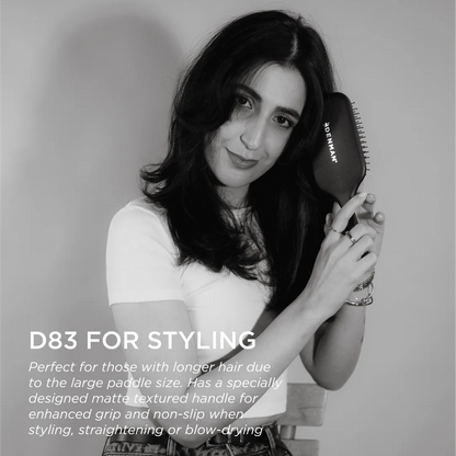 Model holding the Denman D83 The Gentle Paddle Brush, showcasing its ergonomic matte handle and large paddle for styling, straightening and everyday hair care.
