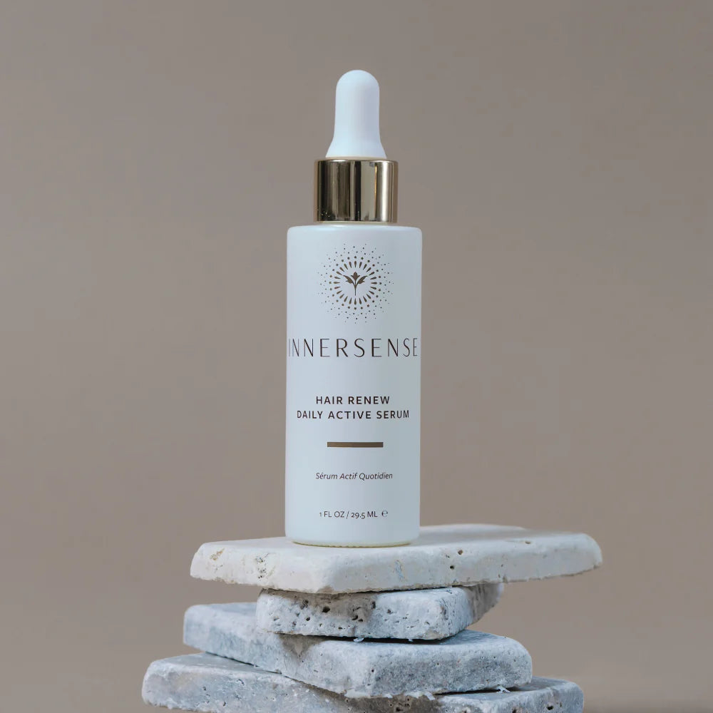 Innersense hair serum bottle on a stone surface with a neutral background