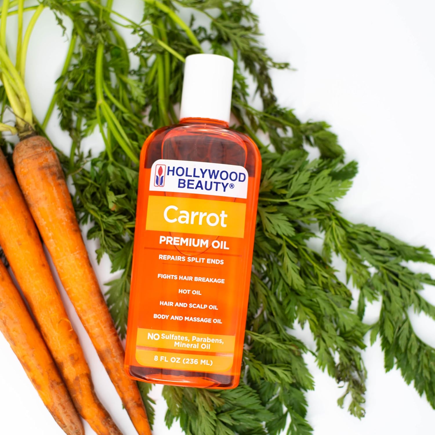 Hollywood Beauty Carrot Premium Oil 8oz / 236ml displayed with fresh carrots, a sulphate-, paraben- and mineral oil-free treatment for split ends, hair breakage, scalp care and body massage