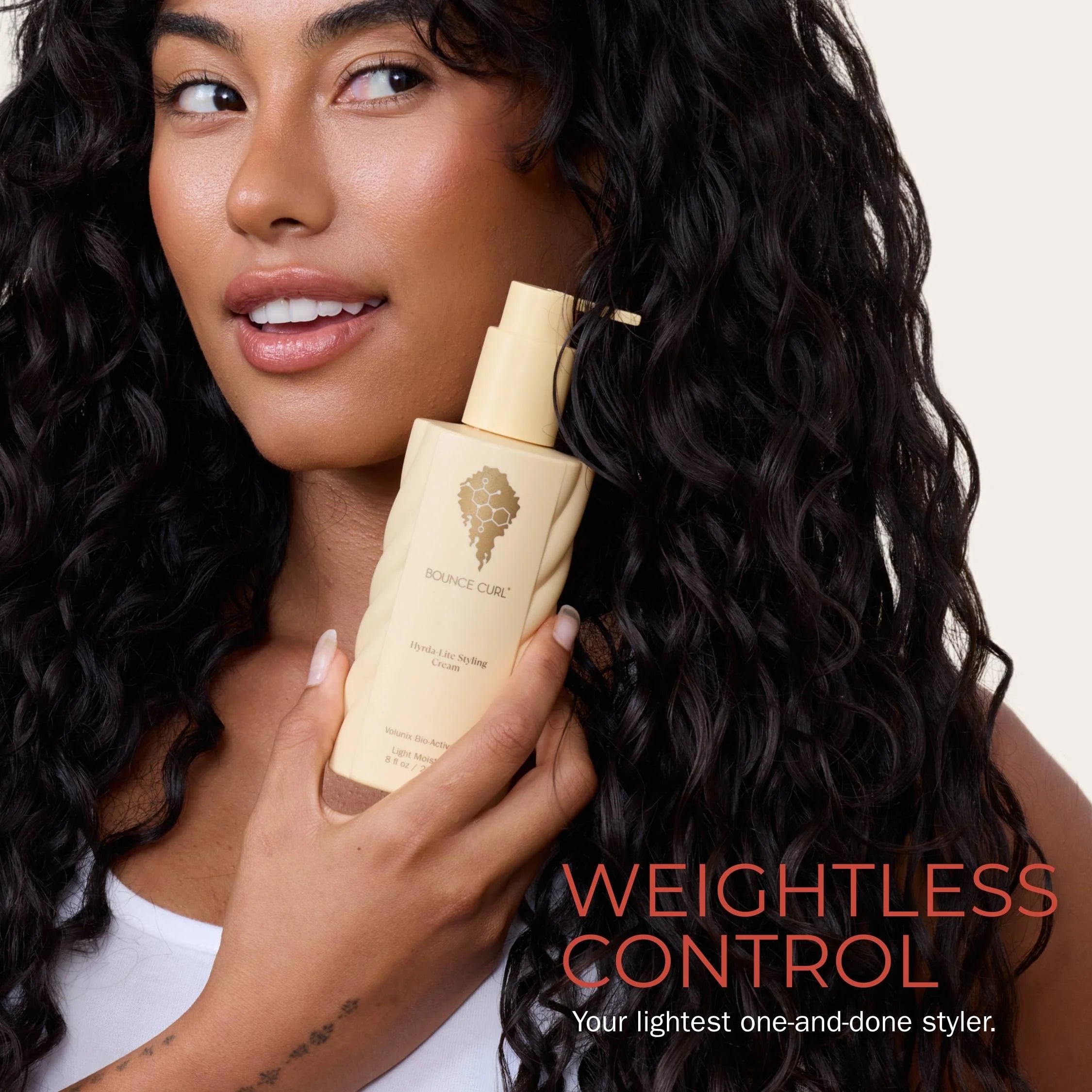 Woman holding a bottle of hydra-lite styling cream with 'Weightless Control' text on a plain background