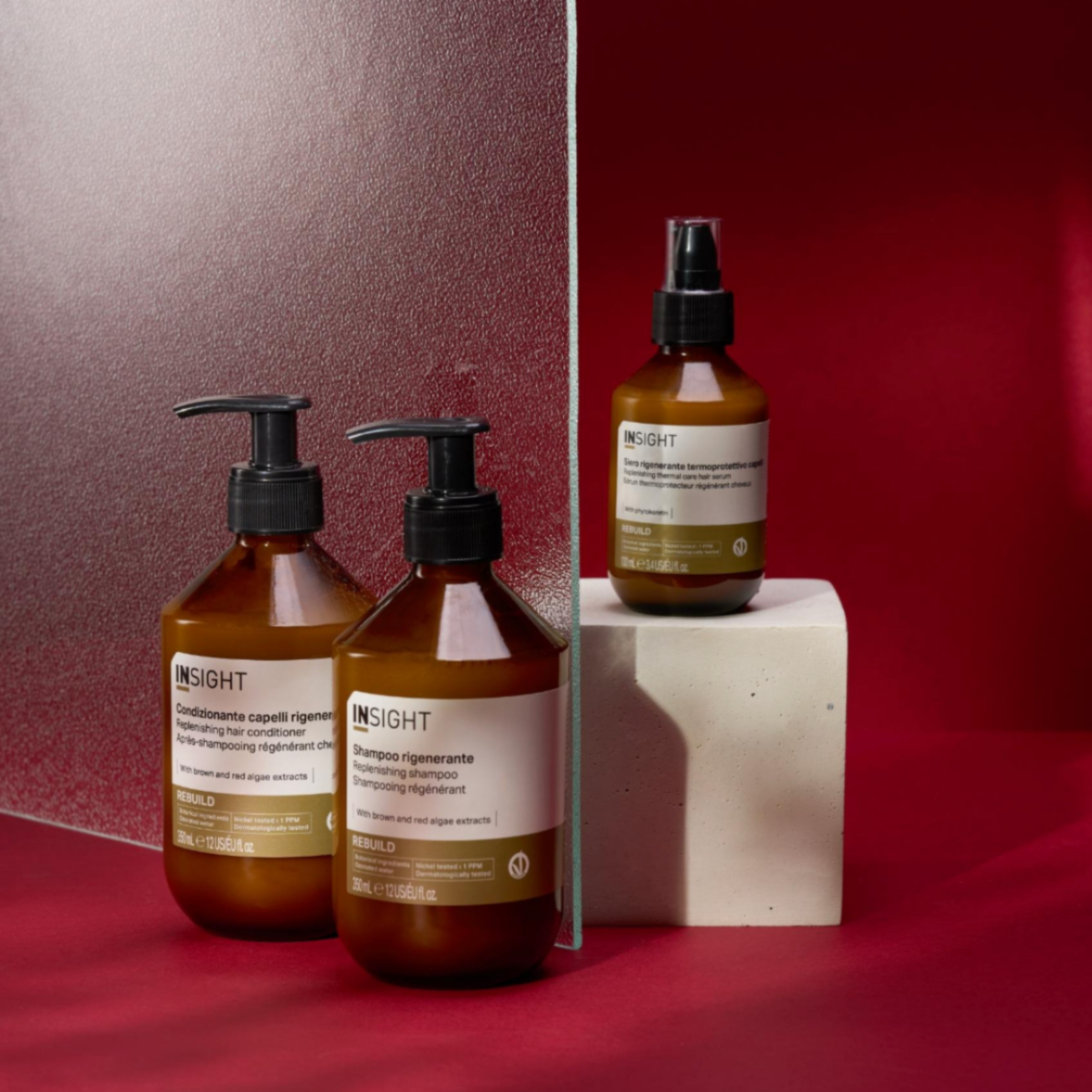 Insight Rebuild Replenishing Shampoo 350ml amber pump bottle displayed with the complete Rebuild range, including shampoo, hair mask and repair serums, on a red background