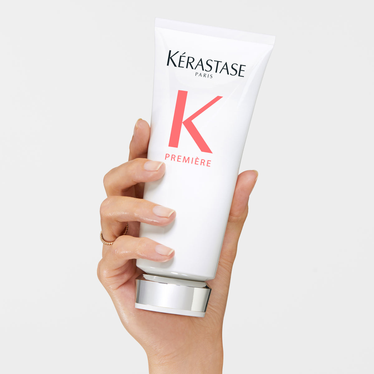 Hand holding a Kérastase Première Fondant Fluidité Réparateur Repairing Conditioner 200ml against a white background