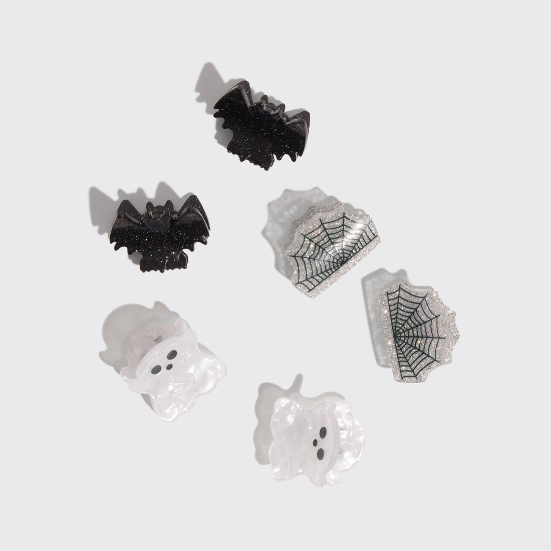 Set of Halloween-themed scrunchies including bats, ghosts, and spider webs on a light gray background.