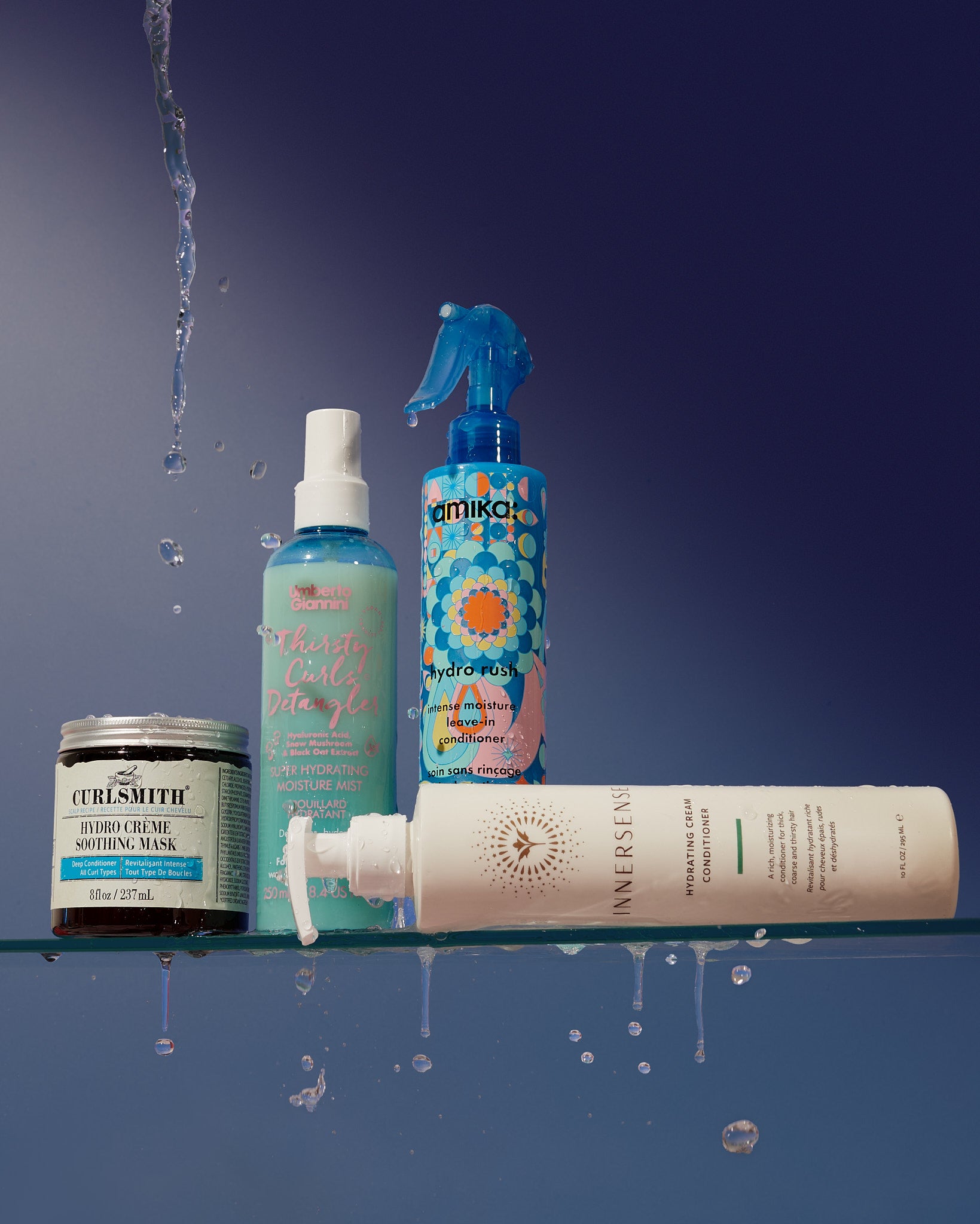 Three winter curl care products on a reflective surface with water droplets against a dark background