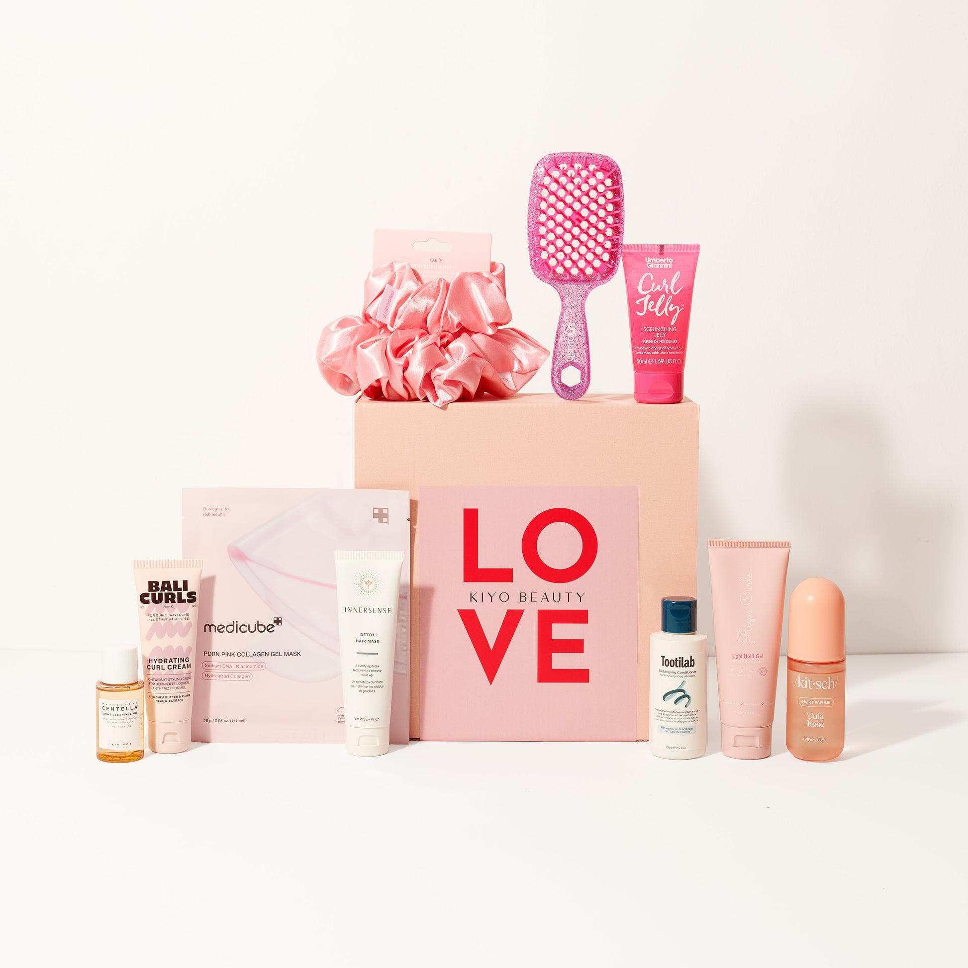 Collection of beauty products including bottles, a brush, and a pink box with 'LOVE' text on a white background.
