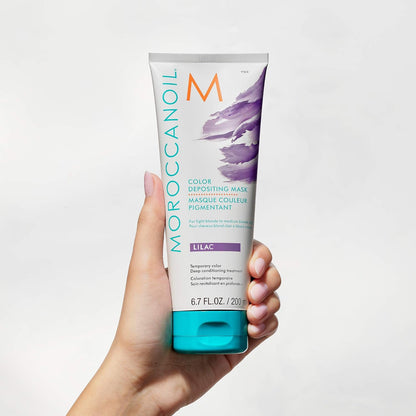 white hand holding Moroccanoil Color Depositing Mask Lilac 200ml