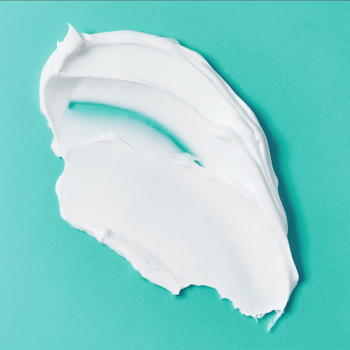 Close-up of rich white Nivea Men Fresh Kick Shaving Foam 200ml texture spread across a vibrant turquoise background, showing its creamy consistency for smooth application.