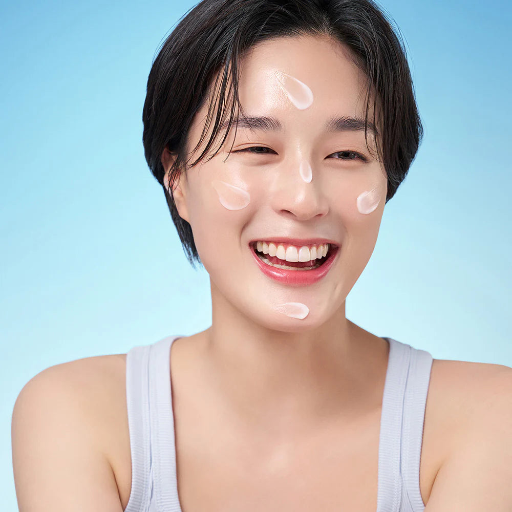 Woman with skincare product on her face against a light blue background