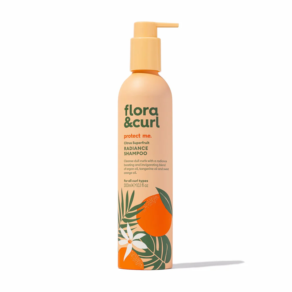 A pump bottle of Flora & Curl Citrus Superfruit Radiance Shampoo with a design featuring citrus fruits and leaves.