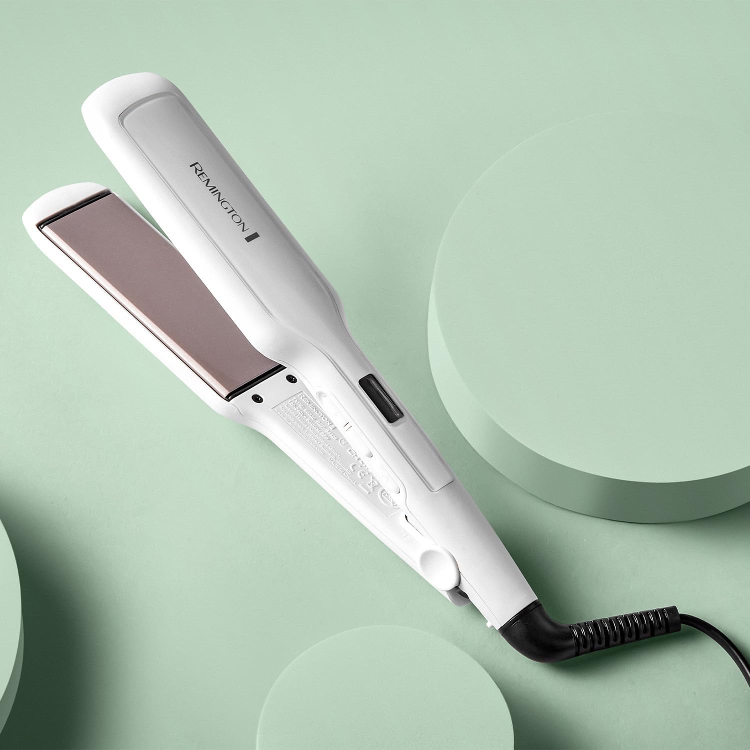 Remington Pro Ceramic Extra Wide Plate Straightener with extra wide ceramic plates and digital controls displayed on a soft green background.