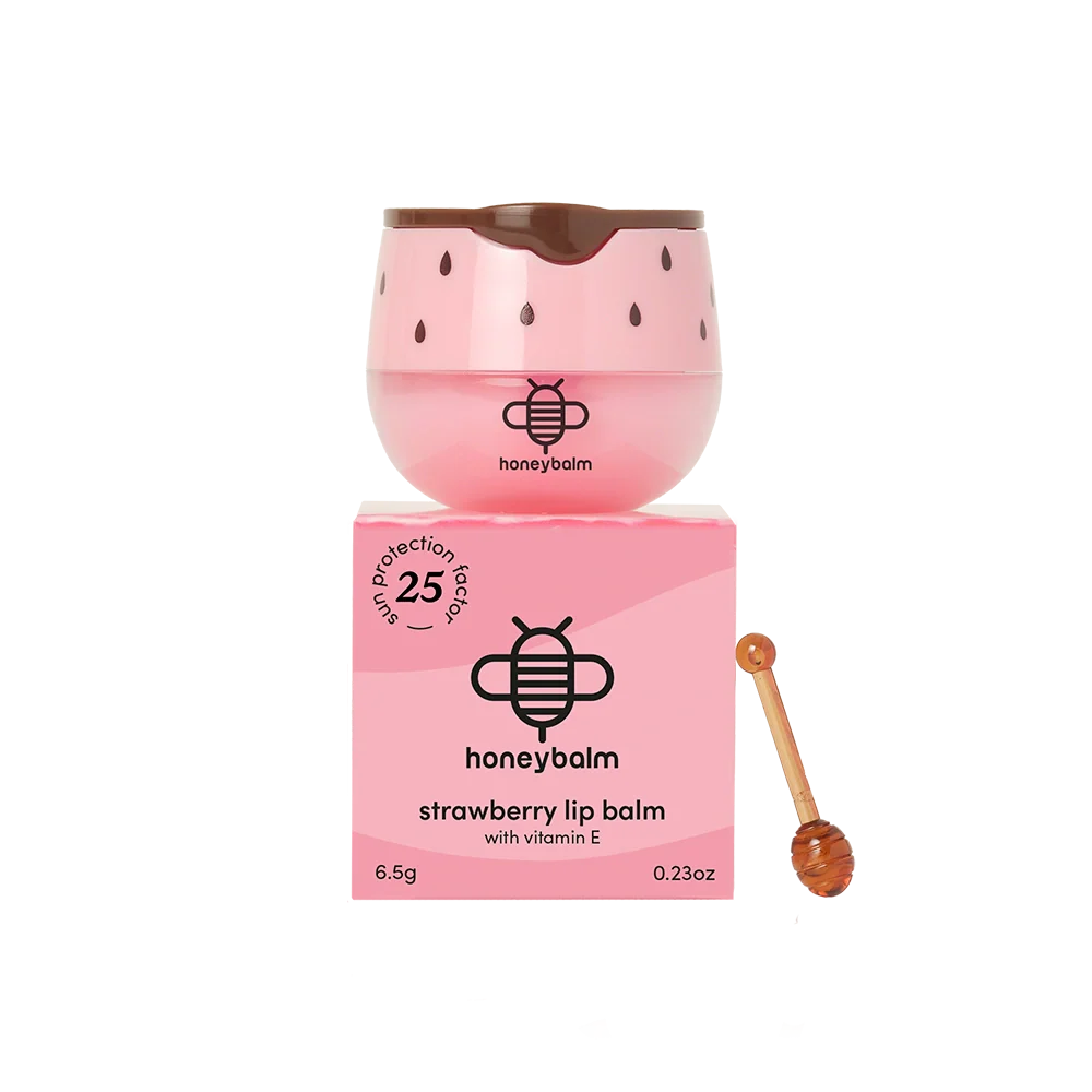 Pink lip balm with strawberry seed design and honeycomb, accompanied by its packaging and a honey stick on a white background.