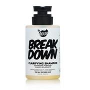 A bottle of The Doux Breakdown Clarifying Shampoo with a black pump, labeled for removing product buildup, designed for all textured hair.