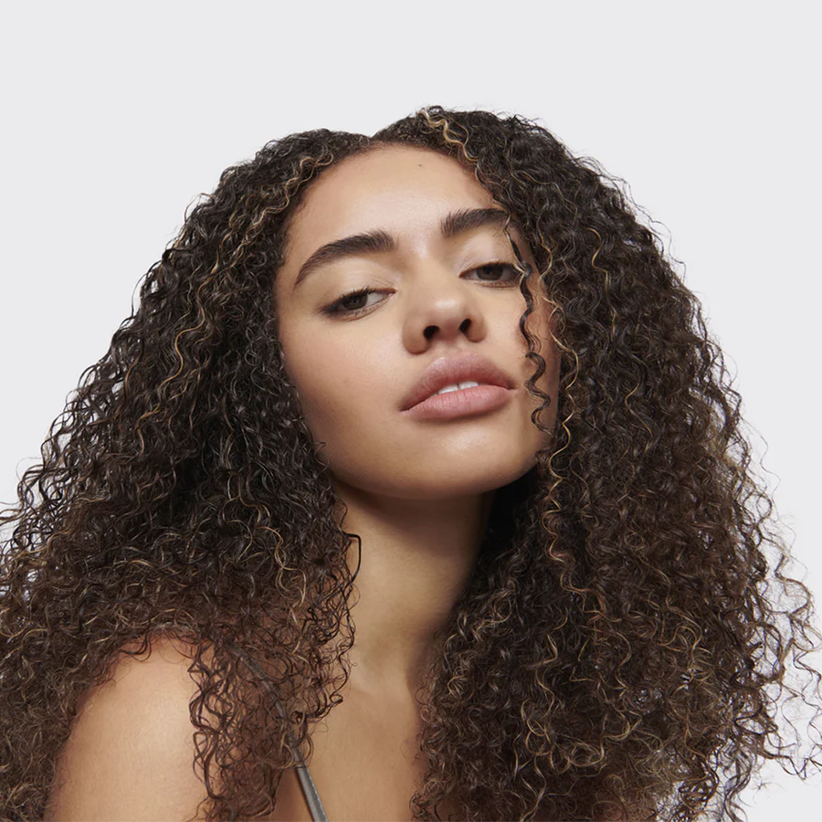 Model with defined, frizz-free natural curls styled using Umberto Giannini WeatherProof Finish Anti-Humidity Frizz Free Hairspray for long-lasting humidity protection.