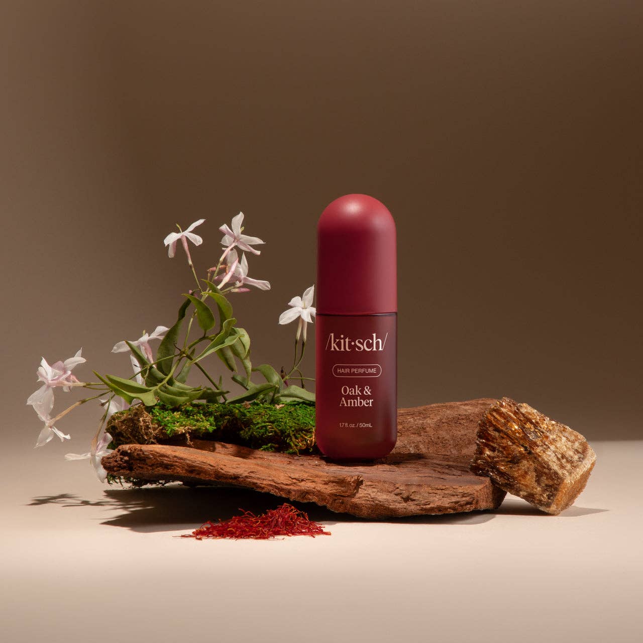Kitsch bottle of Oak &amp; Amber on a wooden platform with flowers and natural elements