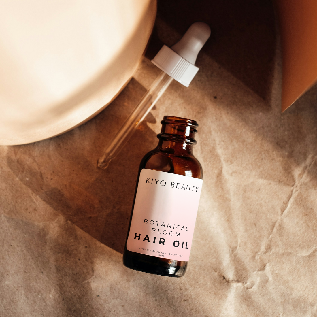 kiyo beauty Hair oil bottle with dropper on a textured surface