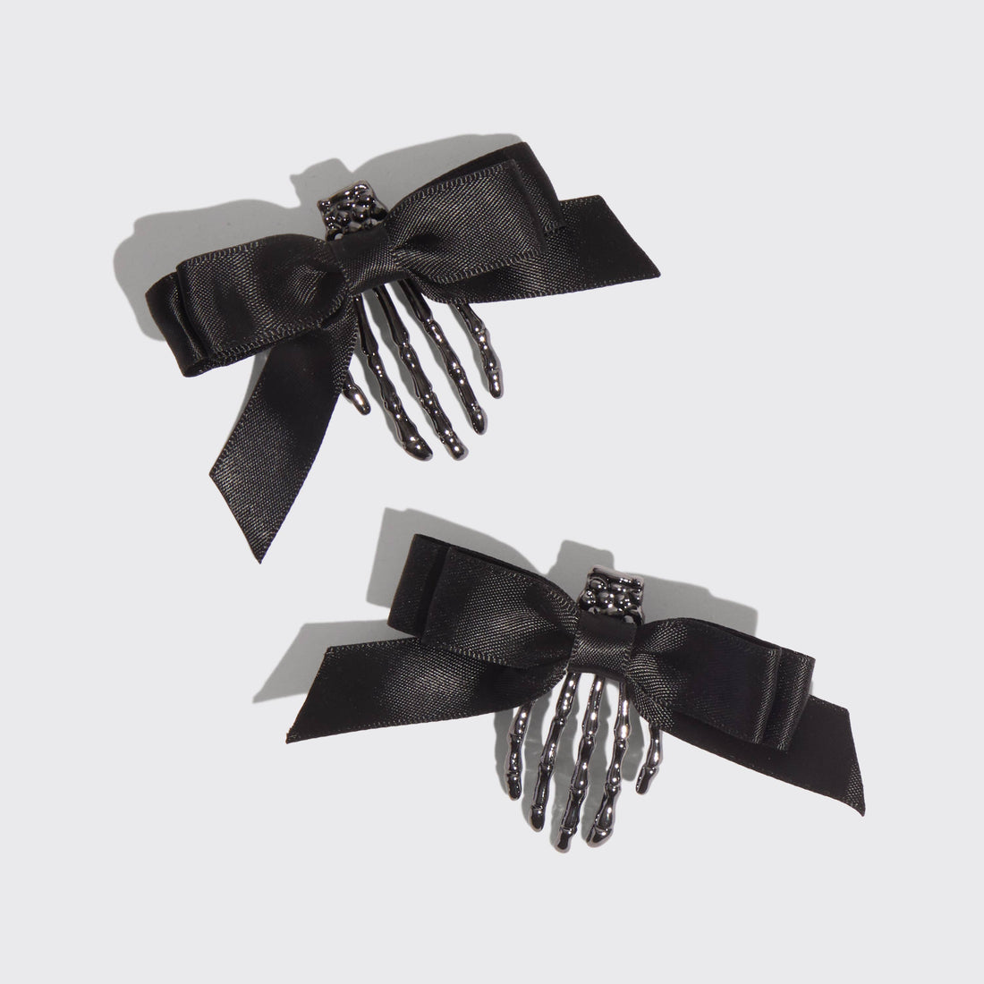 Two black hair combs with decorative bows on a light gray background