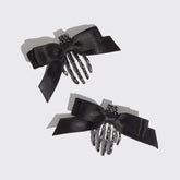 Two black hair combs with decorative bows on a light gray background