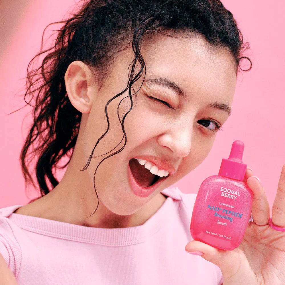equal berry lush blush nad+ peptide boosting serum in a vibrant pink dropper bottle in a woman's hands pink background