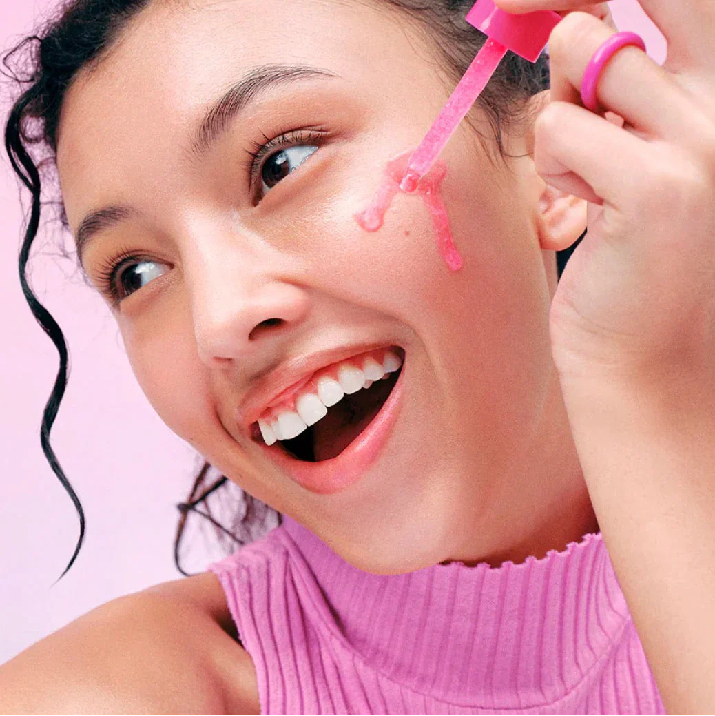 equal berry lush blush nad+ peptide boosting serum in a vibrant pink dropper bottle on a woman's cheek