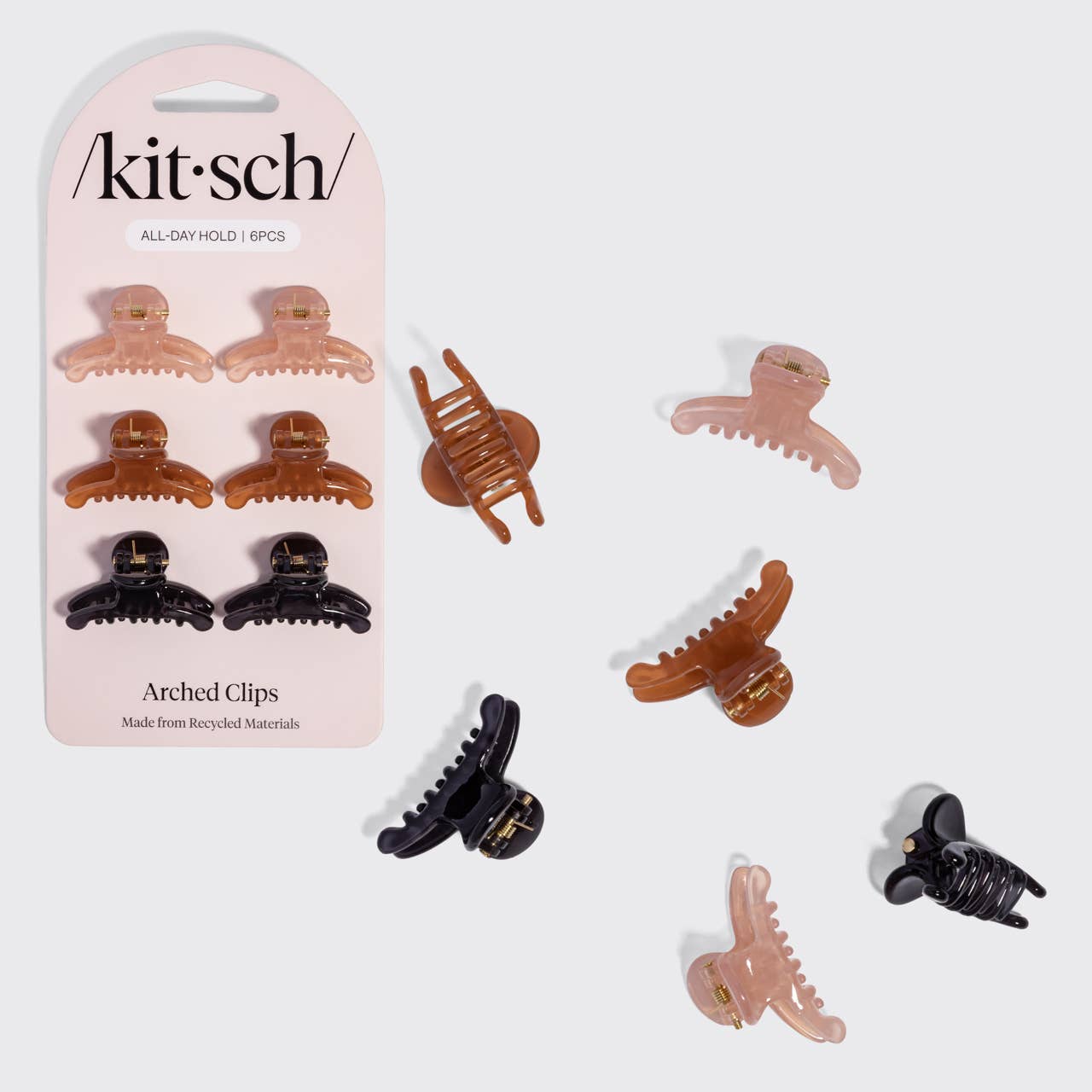 Kitsch Arched Clips set of 8 all-day hold hair clips in assorted colors, shown both on the pink retail card packaging and scattered individually on a light gray background.