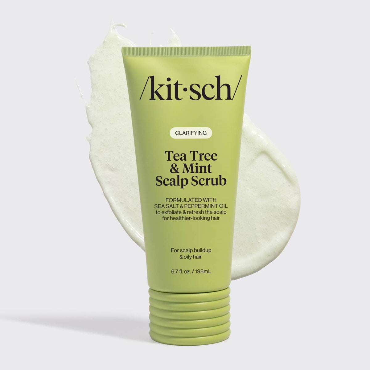 A light green squeeze tube of kitsch Tea Tree & Mint Scalp Scrub, shown in front of a white cream swirl on a light gray background.