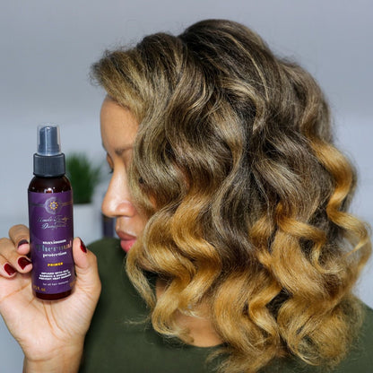 Woman with styled hair holding a purple hair product bottle against a neutral background