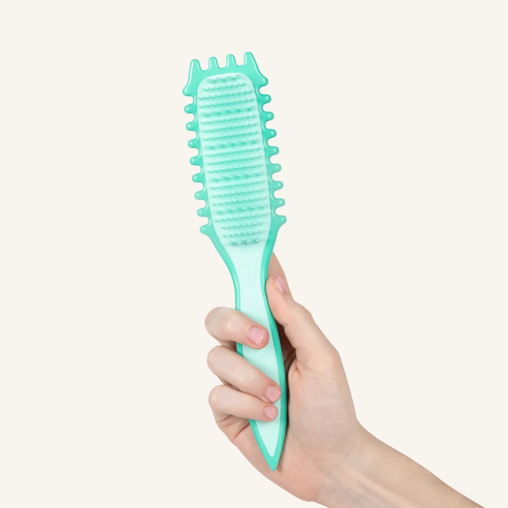 Hand holding a teal Bounce Curl Slick-Flex Define Brush against a light gray background