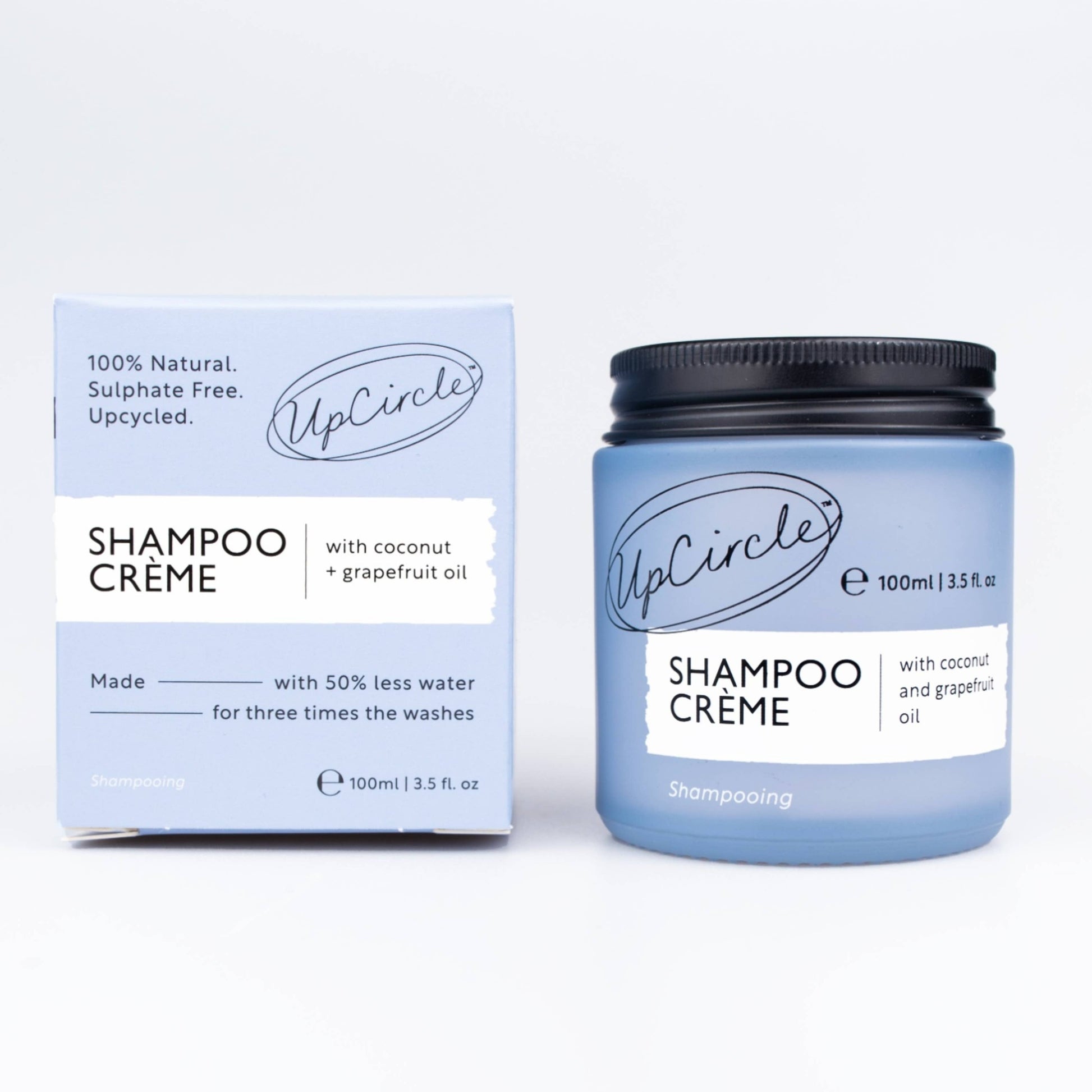 A product image showing UpCircle Shampoo Crème with Coconut + Grapefruit Oil in a blue jar with a black lid, alongside its packaging box.