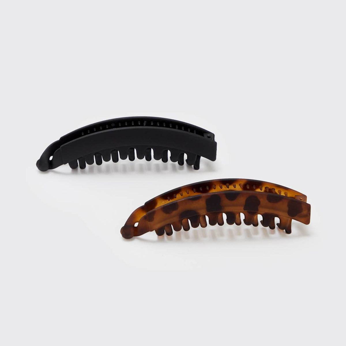 Two banana hair clips, one is black and the other has a tortoise shell pattern.